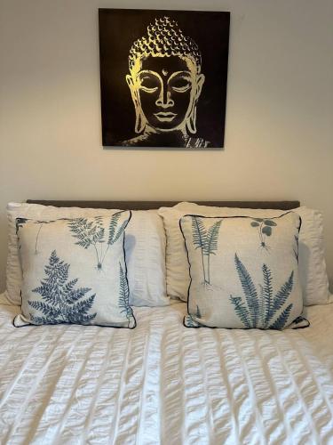 a bed with two pillows and a painting of a head at No 1 Seafield - sleeps 5 - Lincoln City in Lincolnshire