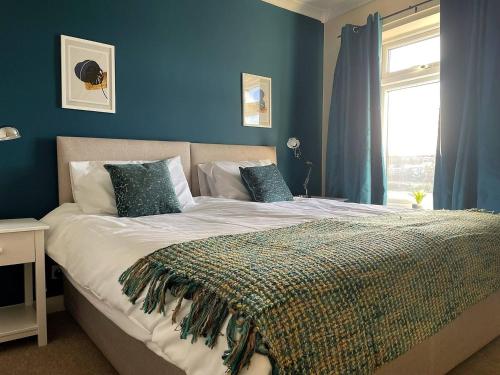 una camera da letto con un letto con pareti blu e una finestra di Station House - 2bed House Central Location a Lincolnshire