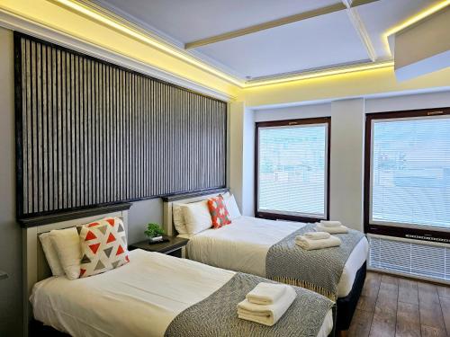 a hotel room with two beds and two windows at London Stay Apartments in London