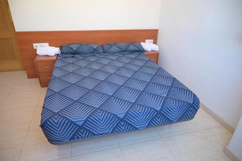 リョレート・デ・マルにあるOliva Marのベッド1台(青と白の掛け布団付)