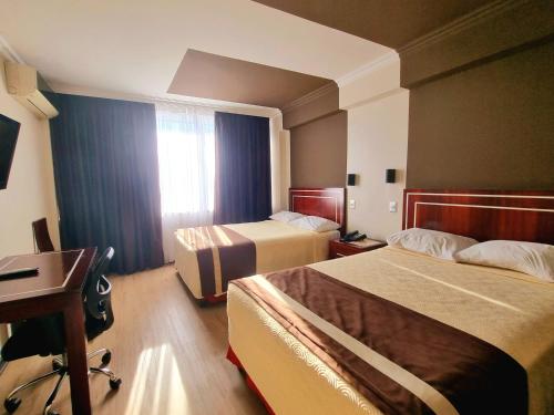 um quarto de hotel com duas camas e uma secretária em Hotel El Araucano em Concepción