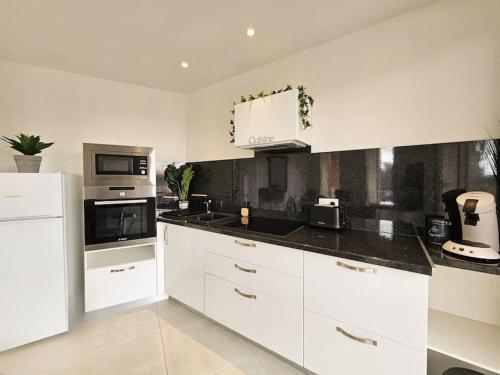 une cuisine avec des armoires blanches et un four à plaques de cuisson dans l'établissement A deux pas du centre Historique, à Fréjus