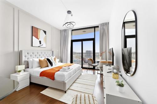 Silkhaus Modern Studio near Silicon Shopping Mall في دبي: غرفة نوم بيضاء مع سرير ومرآة