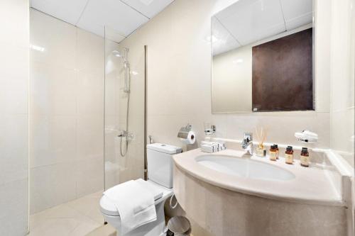 Silkhaus Modern Studio near Silicon Shopping Mall في دبي: حمام أبيض مع حوض ومرحاض