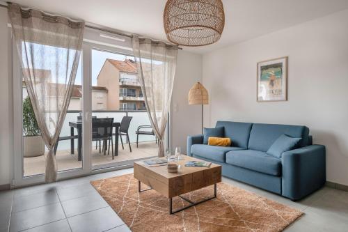 un salon avec un canapé bleu et une table dans l'établissement Appartement pour 4 centre et bord de mer, à Saint-Brévin-les-Pins
