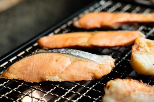 four pieces of fish cooking on a grill at Nara Plaza Hotel in Tenri