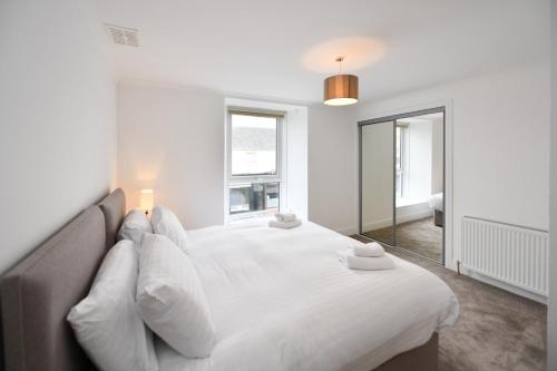 a white bedroom with a large bed with white pillows at Troon Portland Apt B in Troon