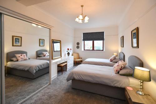 a bedroom with two beds and a mirror at Dunvegan Apartment Troon in Troon