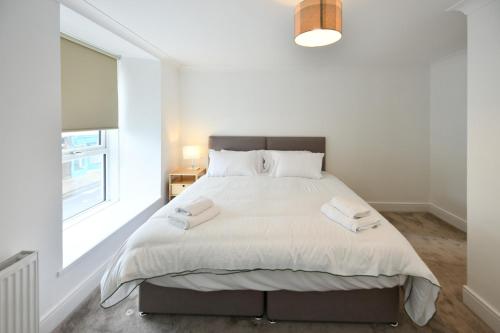 a white bedroom with a large bed with a window at Troon Portland Apt A in Troon