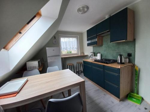 a kitchen with blue cabinets and a wooden table at Pokoje, apartament NA WYSPIE in Gdańsk