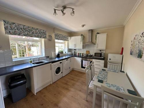 a kitchen with white cabinets and a table with chairs at Comfortable 3 Bed Perfect For Contractors in Lincolnshire