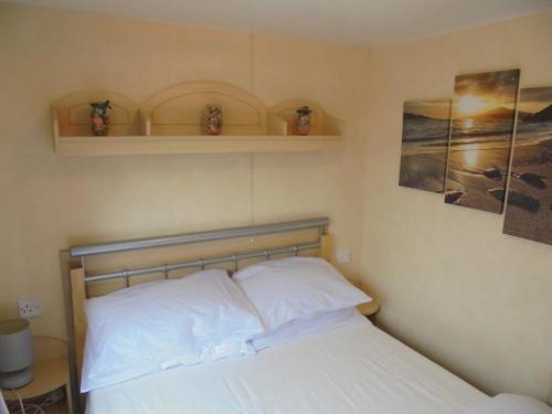 ein Schlafzimmer mit einem Bett und zwei Bildern an der Wand in der Unterkunft 8 Berth on Golden Palm (Florida GP) in Chapel Saint Leonards