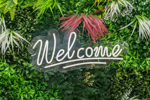 a sign that says welcome in the bushes at Croft Court Hotel in London