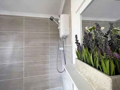 uma casa de banho com um chuveiro com um vaso de flores em Comfortable Contractor Let 4bed em Lincolnshire