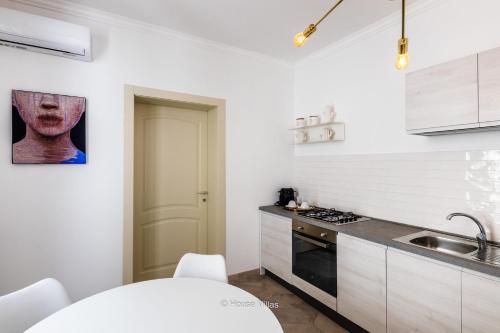 a white kitchen with a sink and a stove at Alma Suite in Noto