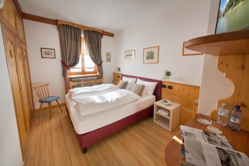 a small bedroom with a bed and a chair at Hotel Posta in Livigno