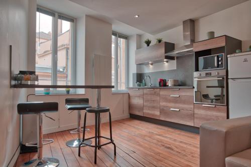 une cuisine avec un comptoir et des tabourets dans une pièce dans l'établissement UnSejourAMetz - Les douillets, du T2 au T3, hyper-centre, à Metz