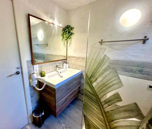 baño con lavabo, espejo y planta en La Villa Verde, en Tarifa