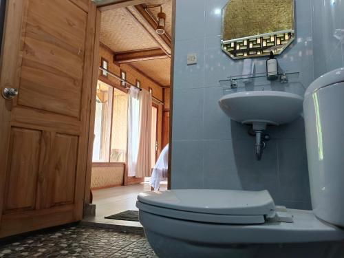 La salle de bains est pourvue de toilettes, d'un lavabo et d'un miroir. dans l'établissement Kraras Munduk Guest House & DonBiyu Rendezvous Restaurant, à Munduk