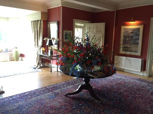a living room with a table with a bouquet of flowers at Fauhope Country House in Melrose
