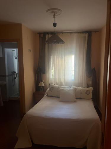 Schlafzimmer mit einem weißen Bett und einem Fenster in der Unterkunft Retiro del emperador in Cuacos de Yuste