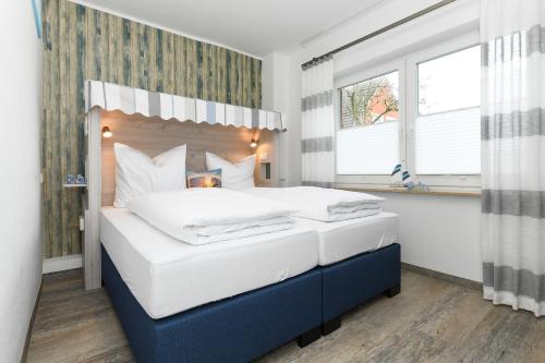 a bedroom with a large bed with white sheets at Haus Strandkorb mit Frühstücksoption in Bensersiel