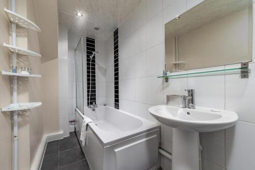 a white bathroom with a sink and a bath tub at The Mount in London