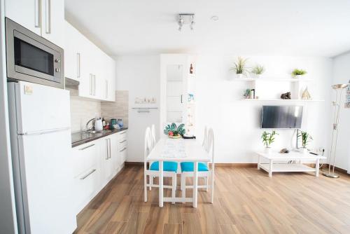 a kitchen with white cabinets and a table with chairs at The 9 souls - pool view in Costa Teguise
