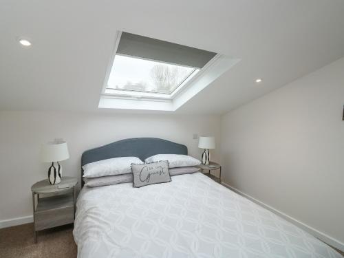 a white bedroom with a bed with a window at Springwell Lodge in Exeter