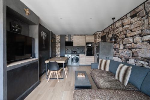 - un salon avec un canapé bleu et un mur en pierre dans l'établissement Esprit Zen - Avec parking 10min à pied de la plage, à Courseulles-sur-Mer