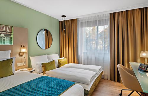 a hotel room with two beds and a window at Leonardo Hotel Esslingen in Esslingen