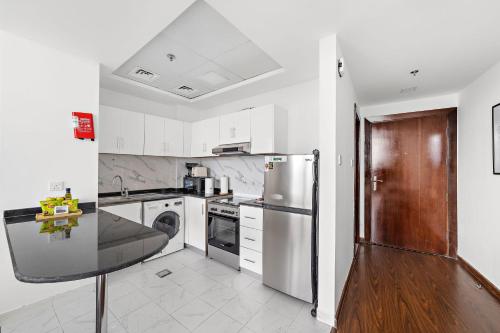a kitchen with white cabinets and a stainless steel refrigerator at Silkhaus Vacation Homes Chic Luxury Studio Opposite Silicon Oasis Shopping Mall in Dubai