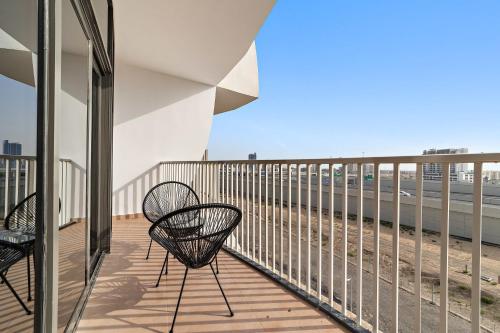 a balcony with two chairs and a view of the beach at Silkhaus Vacation Homes Chic Luxury Studio Opposite Silicon Oasis Shopping Mall in Dubai