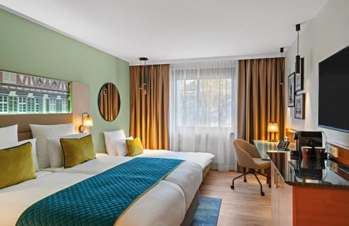 ein Hotelzimmer mit einem großen Bett und einem Schreibtisch in der Unterkunft Leonardo Hotel Esslingen in Esslingen