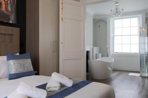 a bedroom with a tub and a bed with towels at Imperial York Street Apartments in London