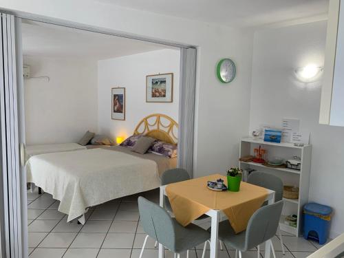 um quarto com uma cama e uma mesa com cadeiras em Casetta nel Giardino -Ischia em Ischia