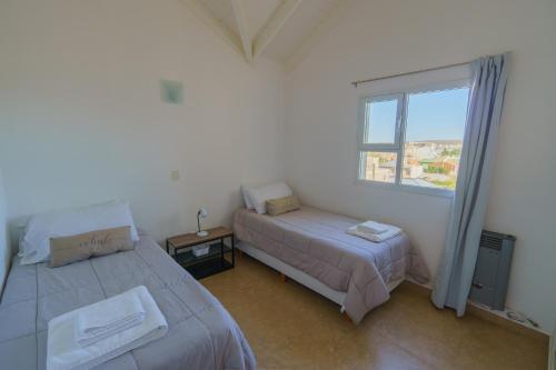 1 dormitorio con 2 camas y ventana en Huemul, cálido y espacioso, aroma de mar en Puerto Madryn