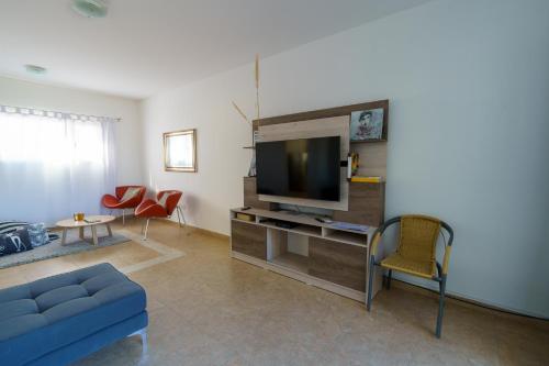 Una sala de estar con un sofá azul y un televisor. en Linea Recta Sur- Huemul, departamento amplio, de 3 dormitorios a pasos del mar, en Puerto Madryn