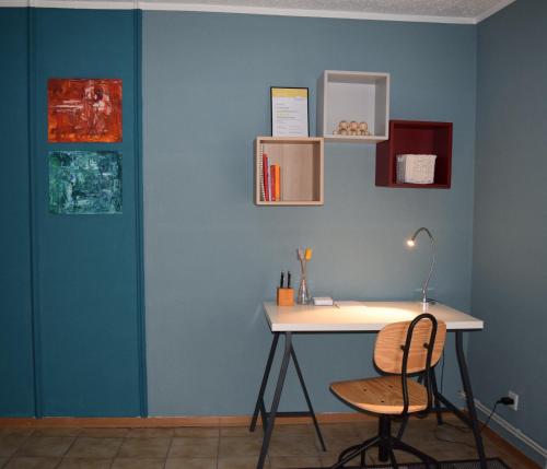 a desk and chair in a room with a blue wall at Ferienwohnung auf dem Dorf, Külsheim in Külsheim