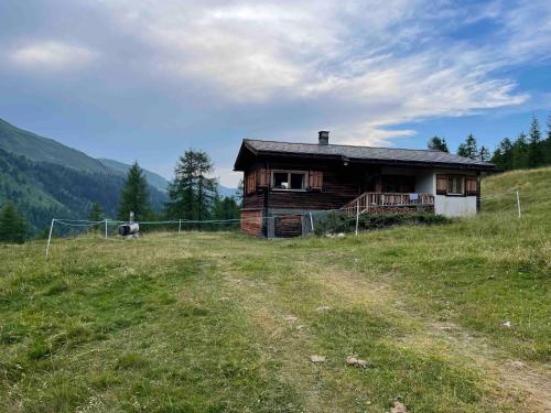 a wooden house on a hill with a field at Zauberberg in voller Pracht in Sertig Döfli