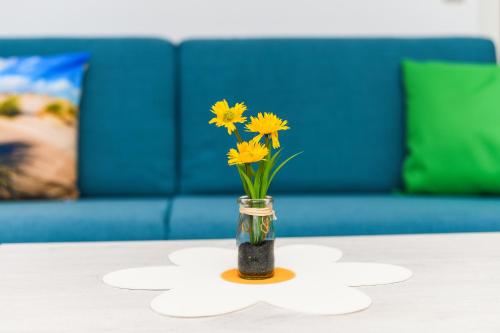 a vase filled with yellow flowers on a table at Haus Strandkorb mit Frühstücksoption in Bensersiel