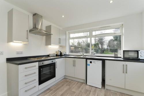 a kitchen with white cabinets and a window at Spacious 5-bed House Private Parking in Newark upon Trent