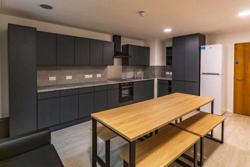 a kitchen with a wooden table and a refrigerator at Modern Stylish Ensuite at Student Roost Buchanan View in Glasgow for Students Only in Glasgow