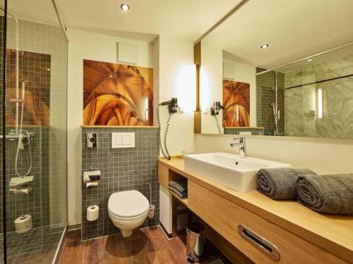 a bathroom with a sink and a toilet and a shower at Augustiner Hotel in Hillesheim