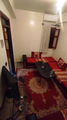 - un salon avec une télévision, un canapé et une table dans l'établissement Appartement situé à 5 minutes à pied de l'Aeroport de Marrakech, à Marrakech