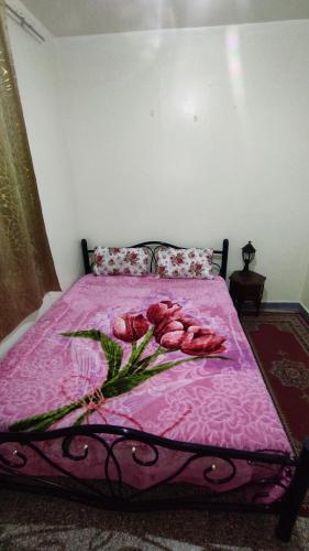 un lit rose avec une bande de roses sur le lit dans l'établissement Appartement situé à 5 minutes à pied de l'Aeroport de Marrakech, à Marrakech