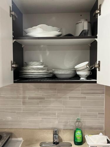 a kitchen cabinet with plates and dishes in it at Bernie's Basement in Milton