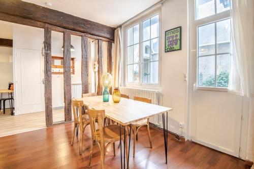 une salle à manger avec une table, des chaises et des fenêtres dans l'établissement Follow the arrow - Nice flat in the city center, à Tours