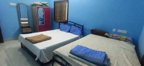 2 Betten in einem Zimmer mit blauen Wänden in der Unterkunft PR Residency in Tiruvidaimarudūr