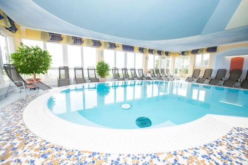 a large swimming pool with chairs in a building at Familienhotel Berger in Sankt Jakob im Walde